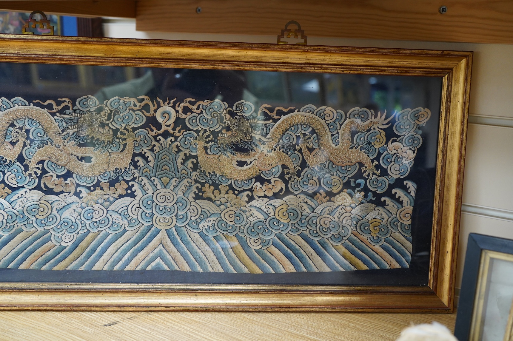 A framed late 19th / early 20th century Chinese silk embroidered five claw dragon panel from the base of a robe, 59cm wide x 23cm high. Condition - good, colours and embroidery strong
